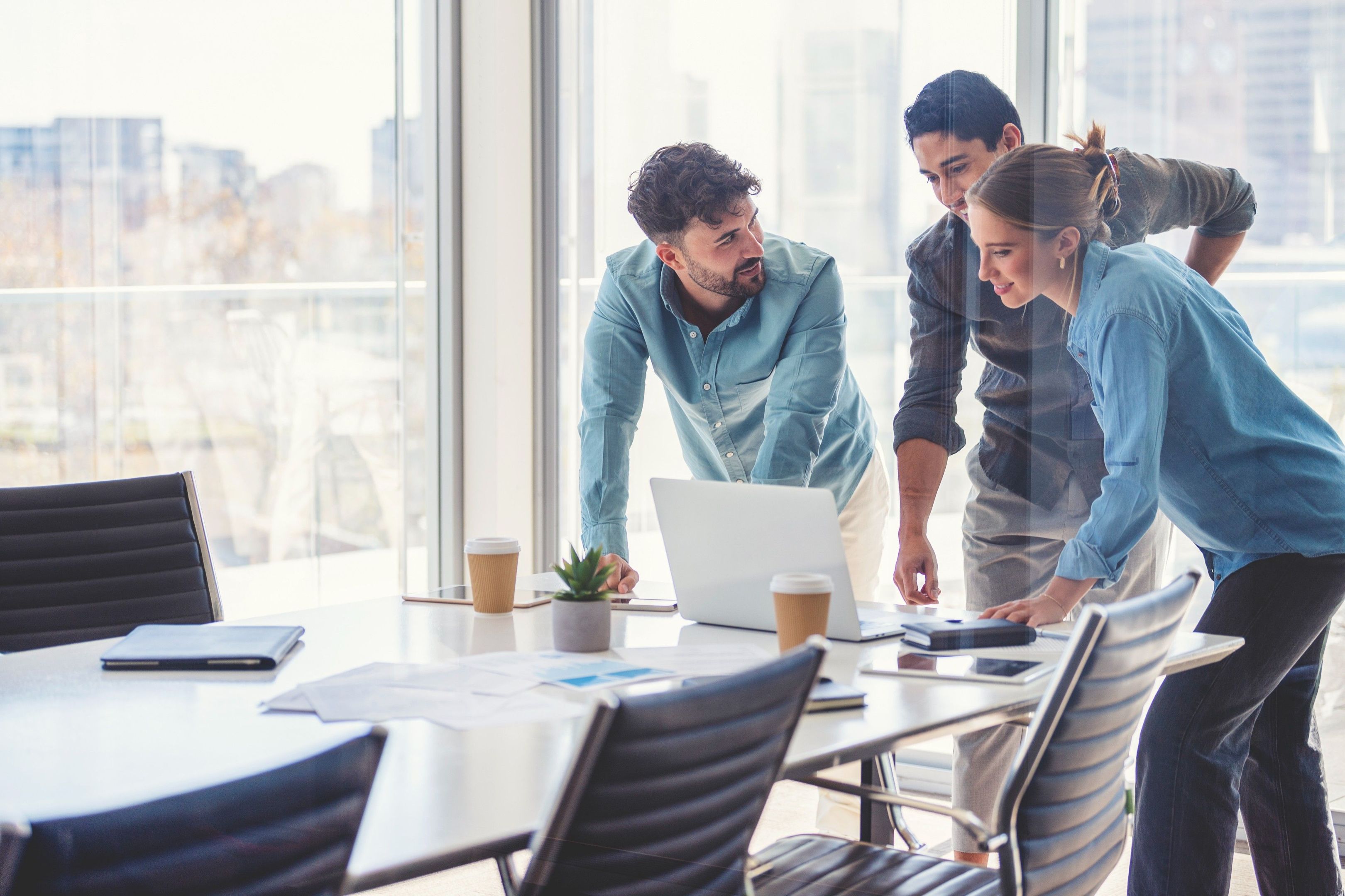Team gathers around a laptop in a modern office, representing secure access to shared files in the cloud.