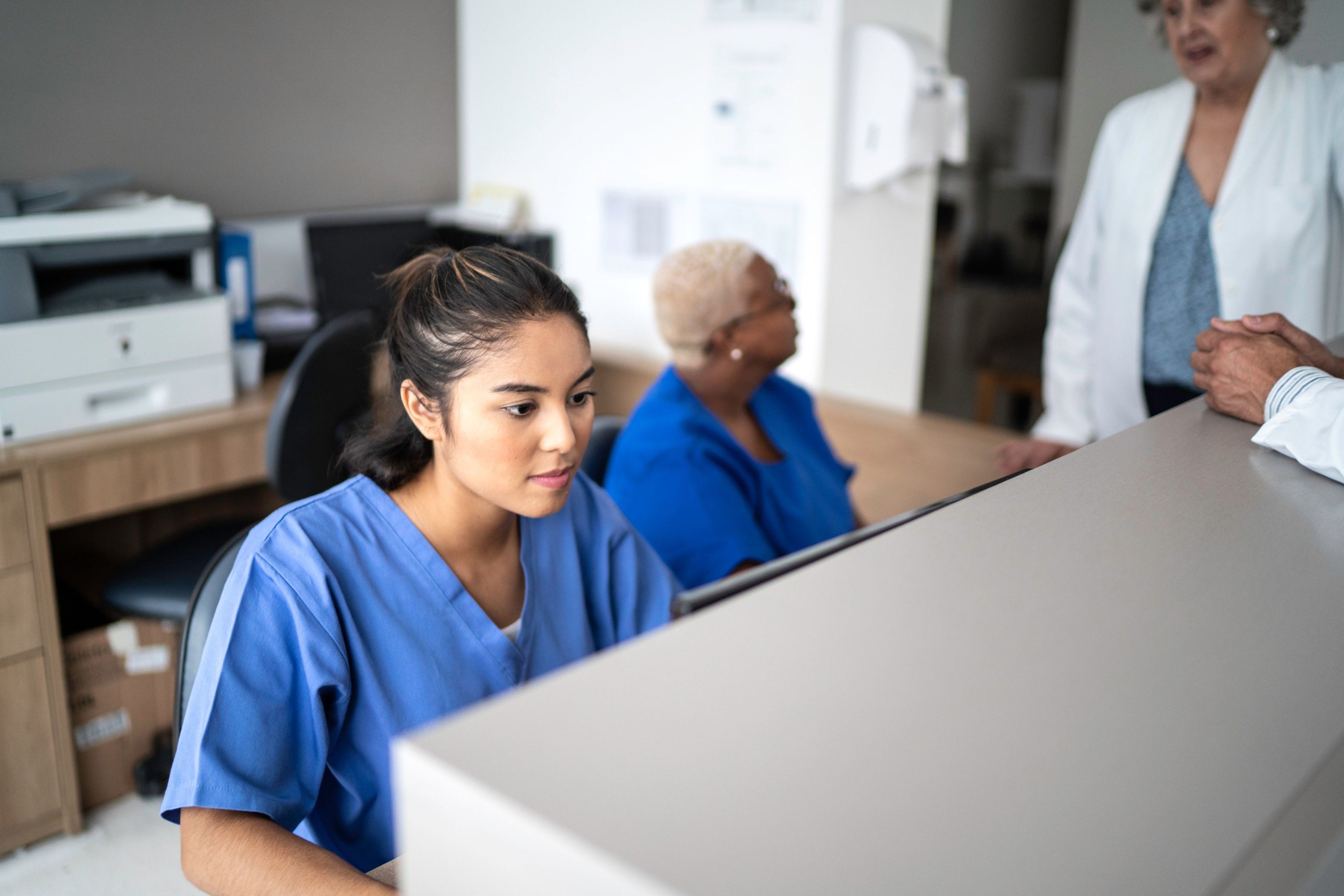 Female in scrubs working at a computer