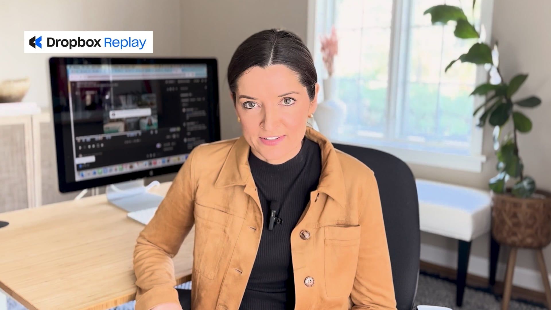 Woman at desk in home office with Dropbox Replay on screen and logo in top left corner.