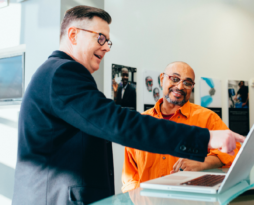 Collaborators gesturing towards an opened laptop