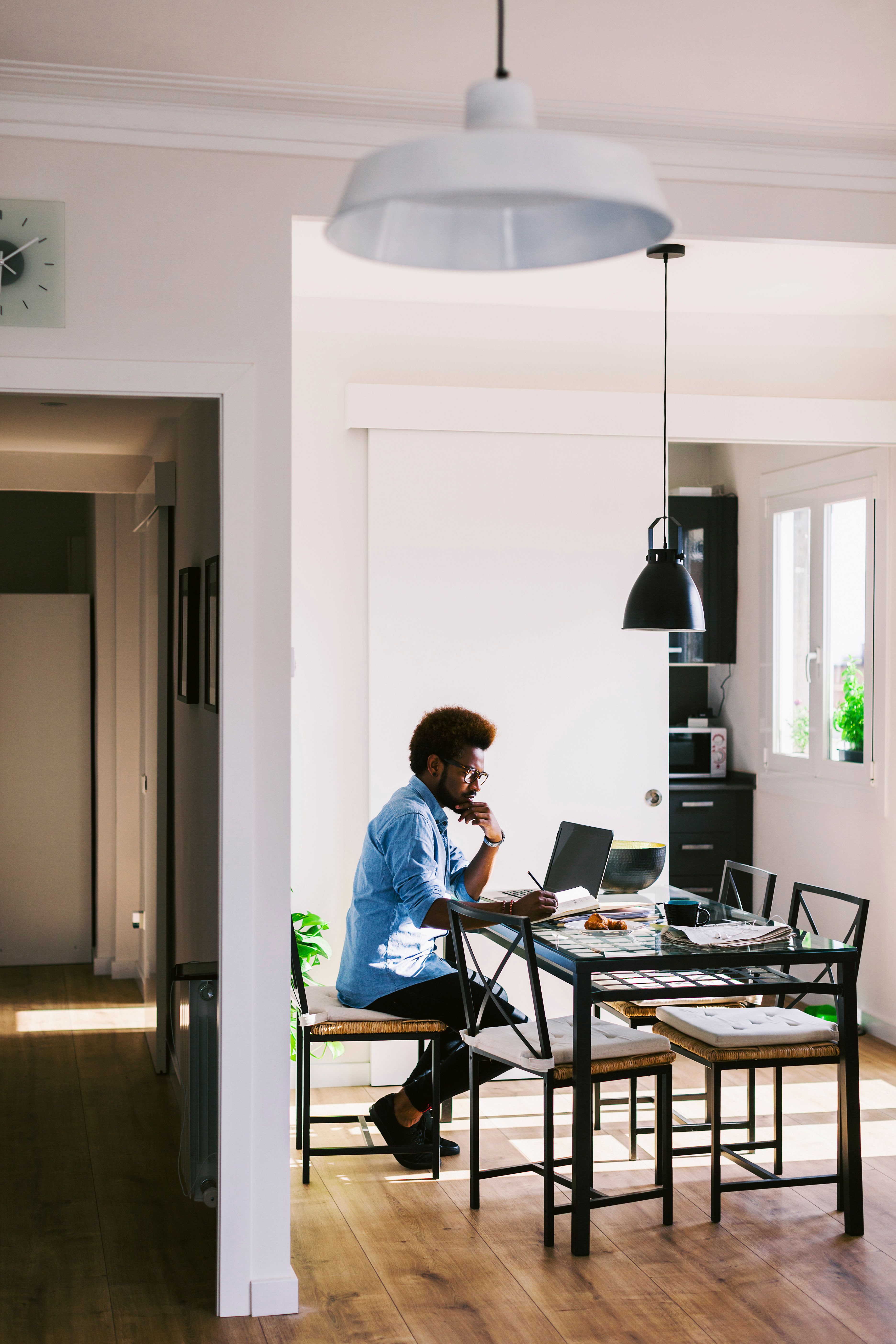 A person working from home with a laptop and a notebook.