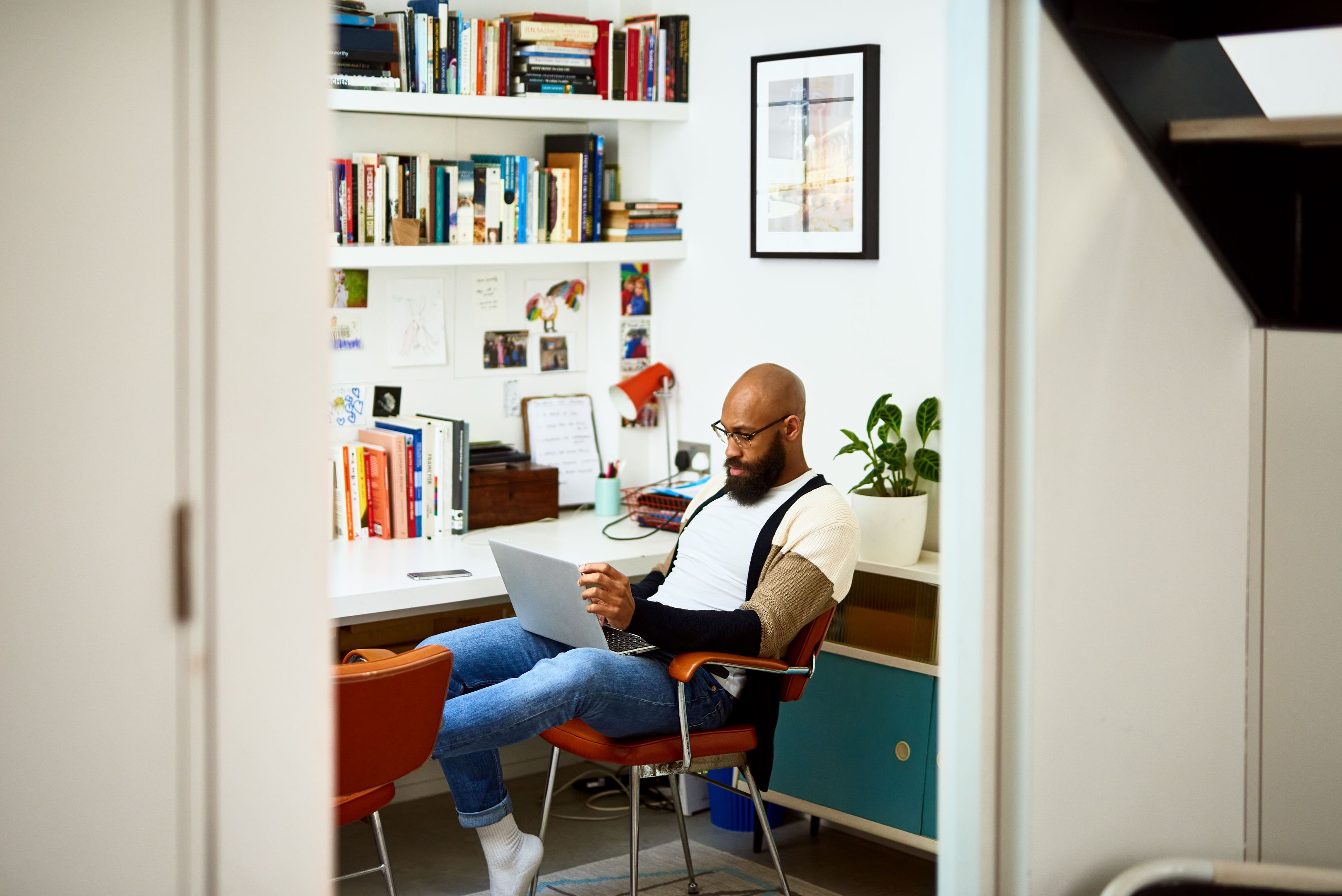 A person sitting turned away from their desk, working with their laptop on their lap.
