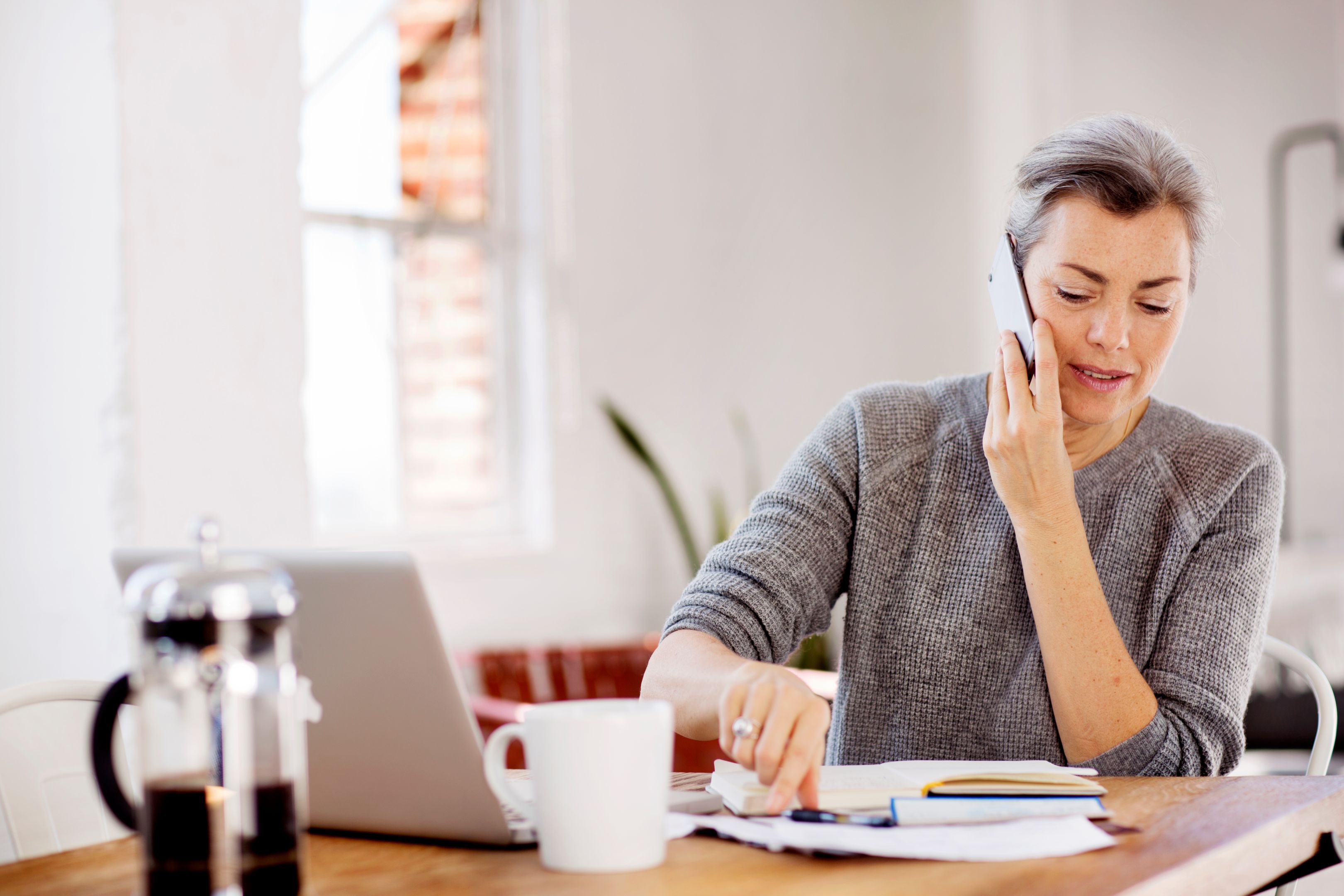 A person sits looking through files while on their mobile device.