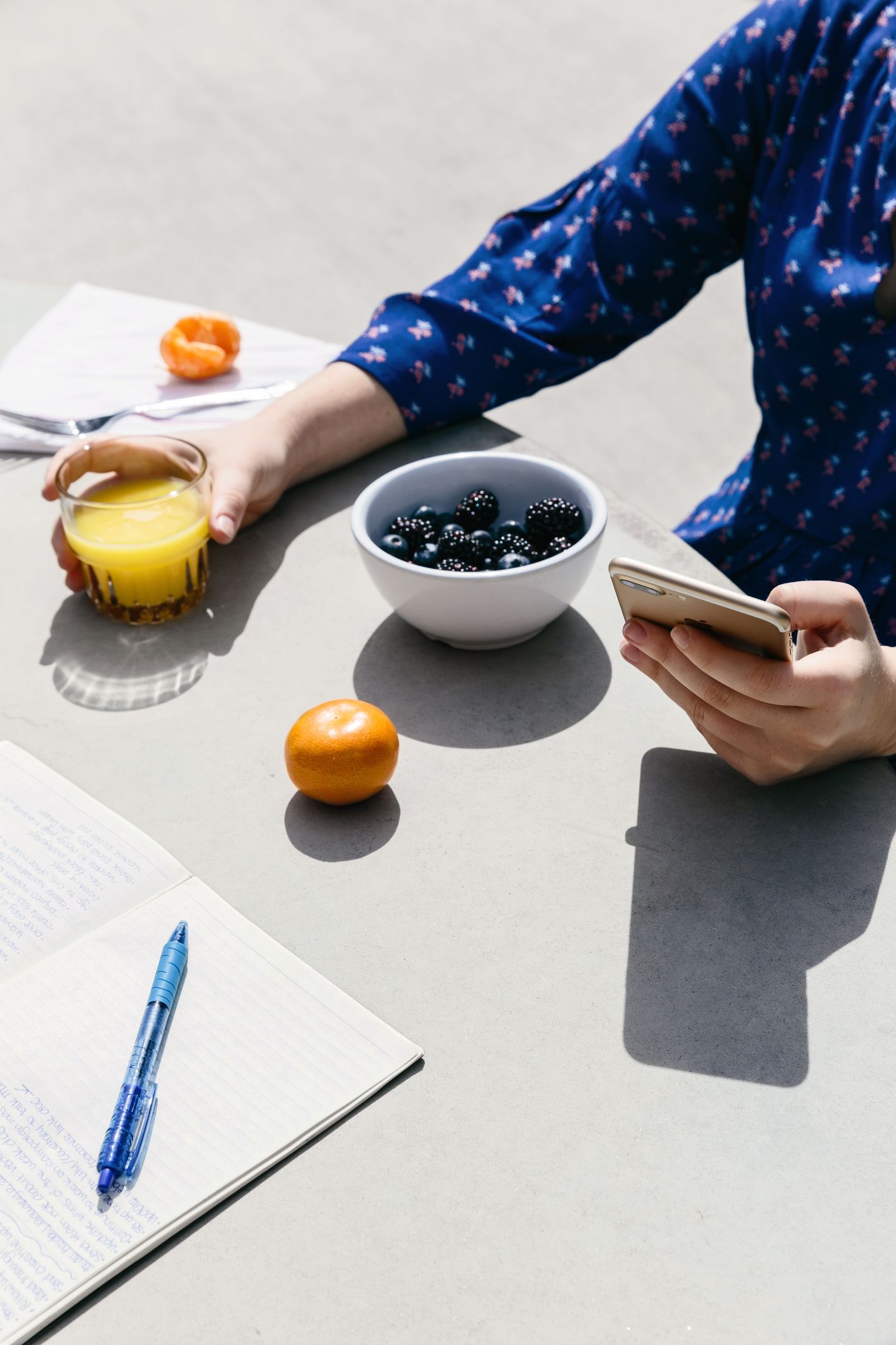A person looks at their mobile device while eating breakfast outdoors.