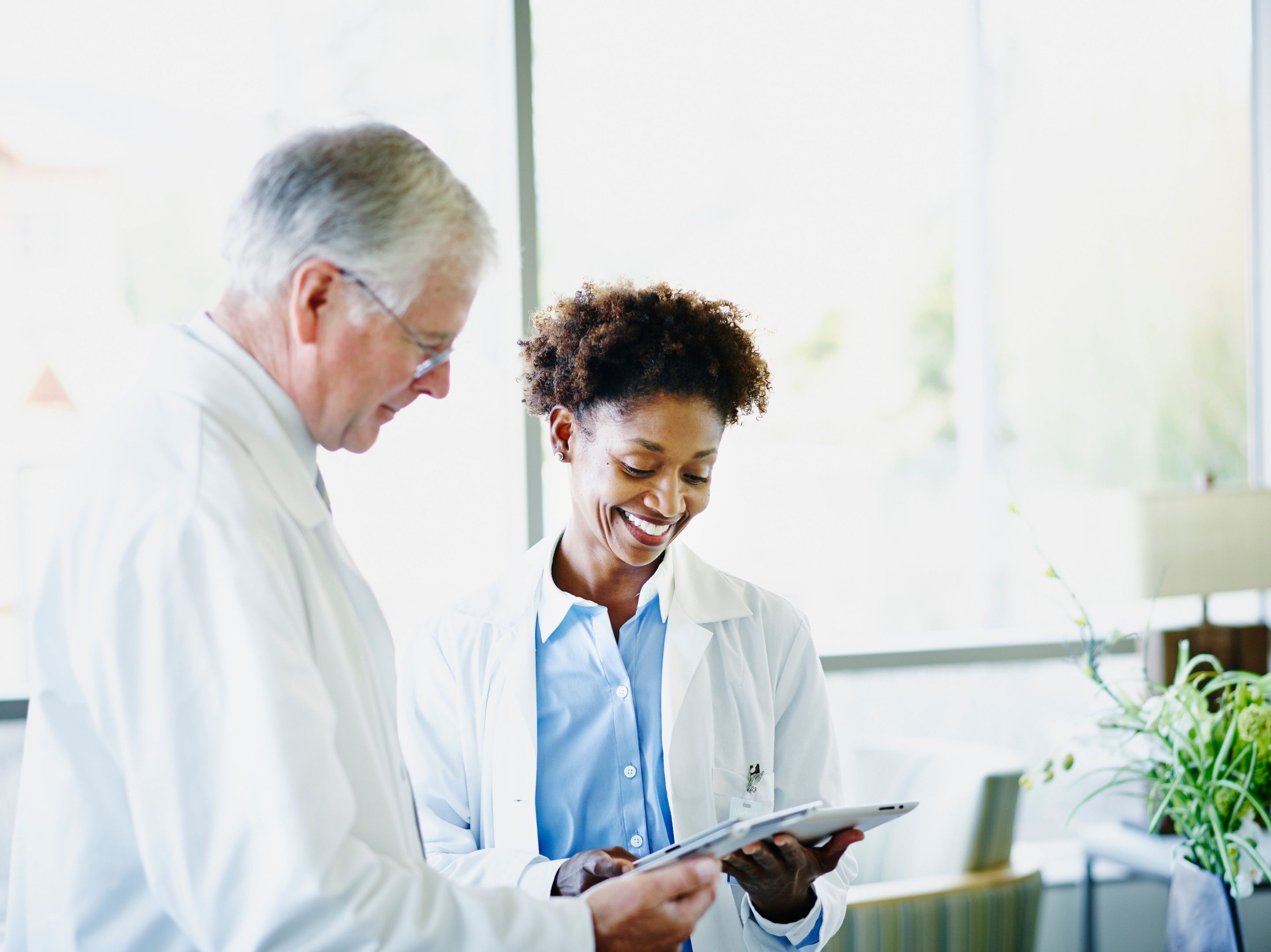 Two medical professionals review information on a tablet, representing secure collaboration through encrypted file sharing.