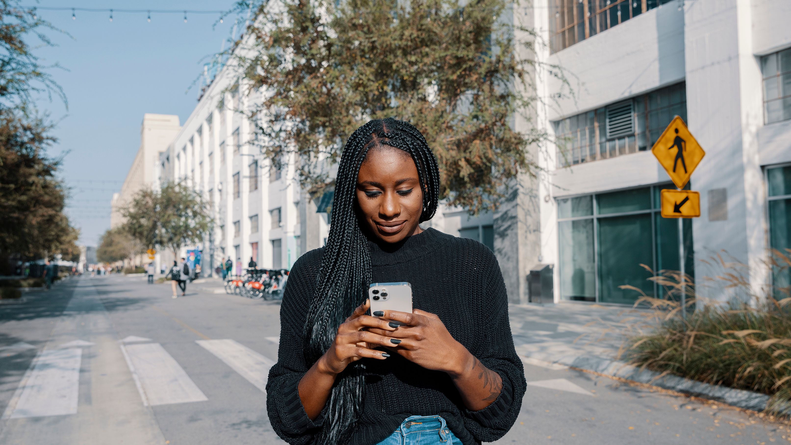 A person standing in the middle of a quiet road while on their mobile device.