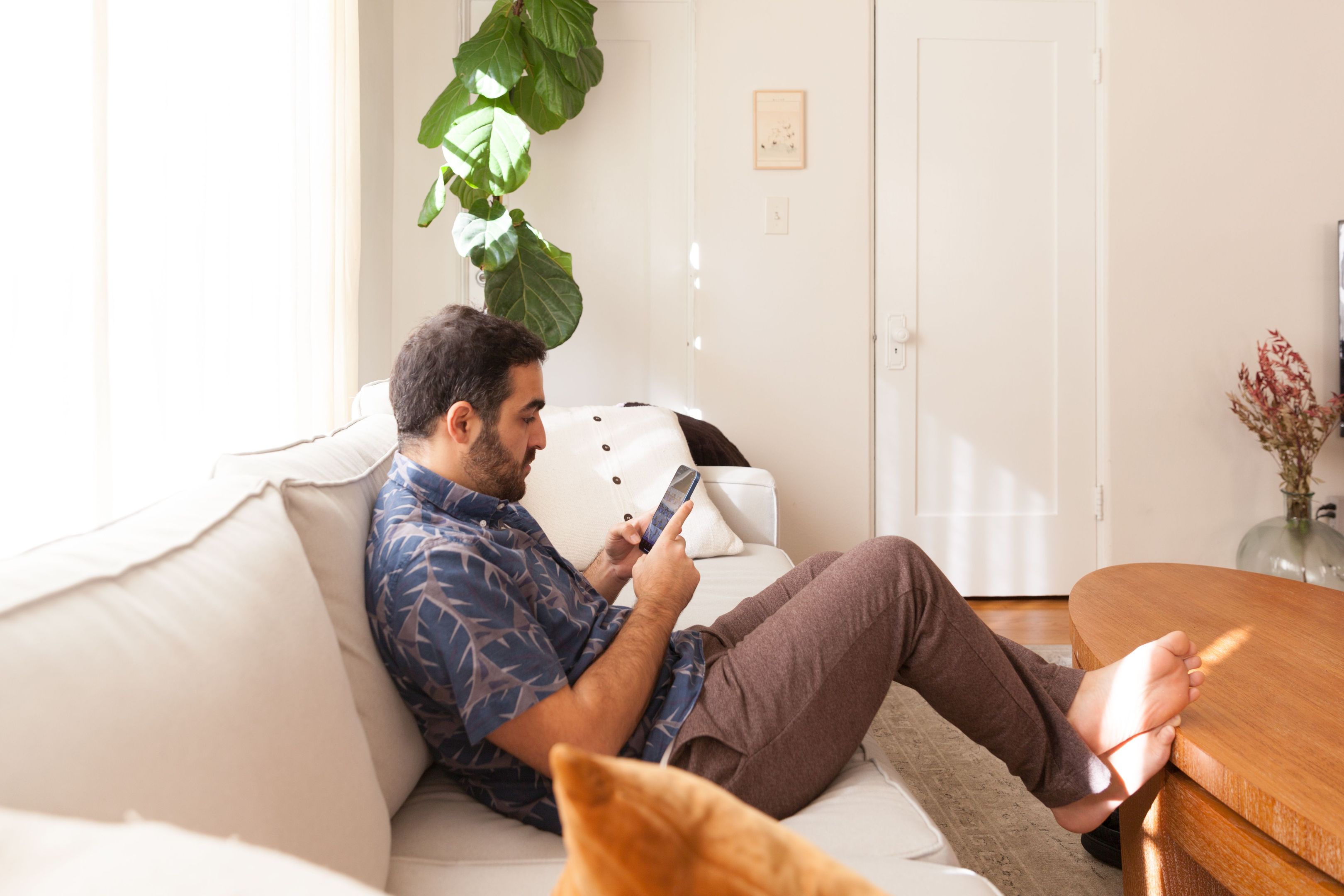 A person looks at their mobile device while sitting on a couch.