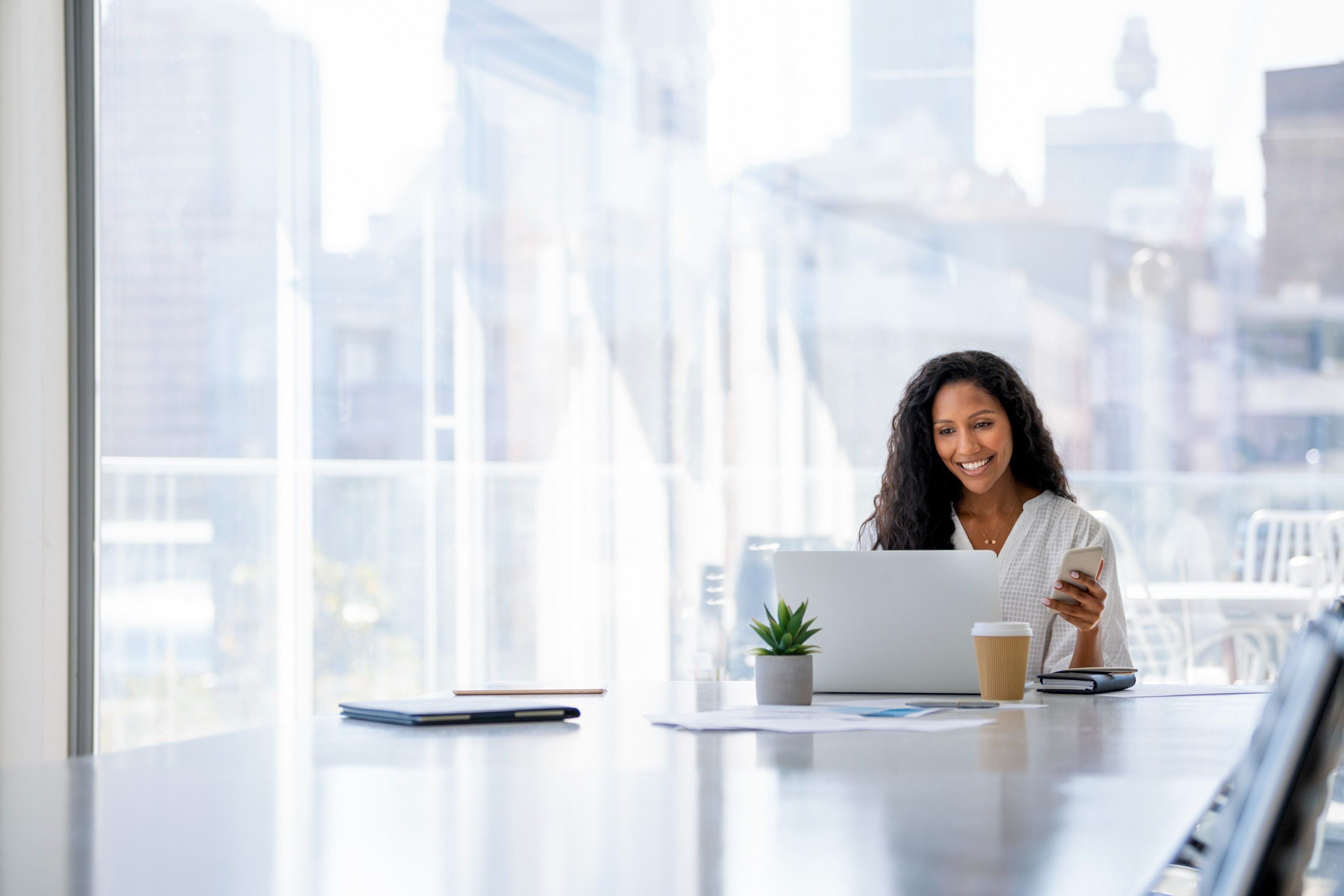 A person sits at a desk in an office meeting room, smiling after recovering their files on their laptop.