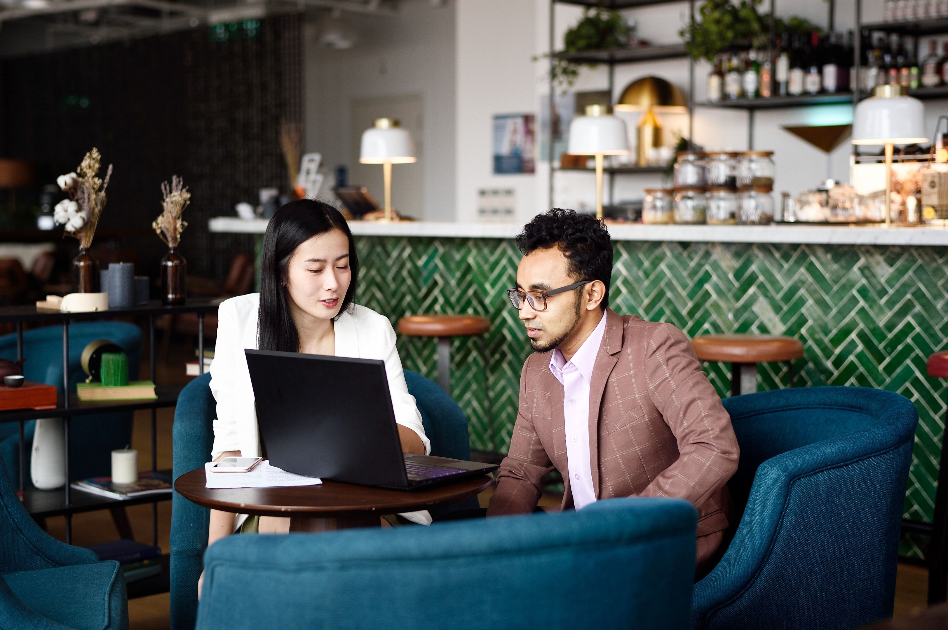 Two people look at a laptop.