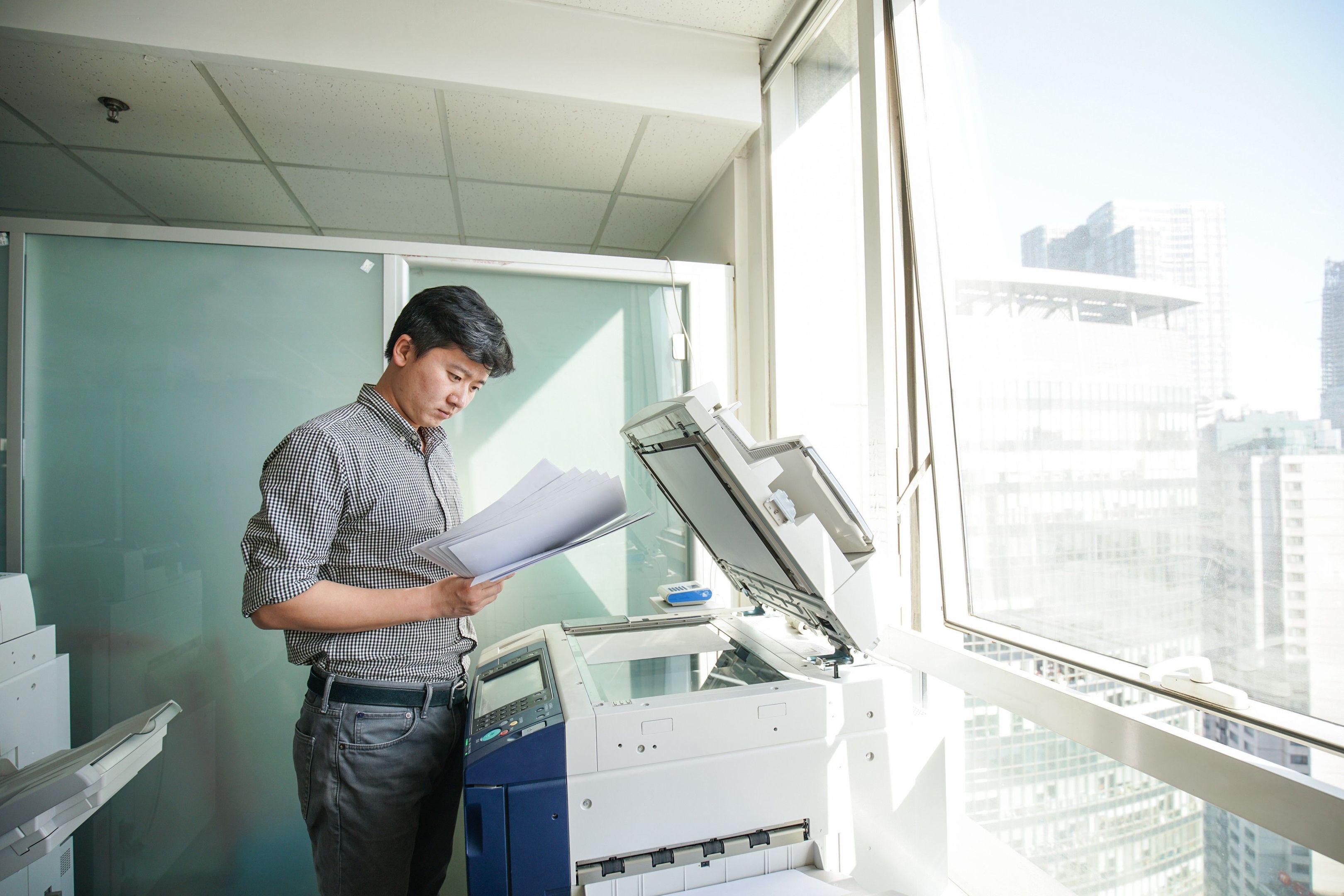 Photograph of a person using an office printer to scan a document.