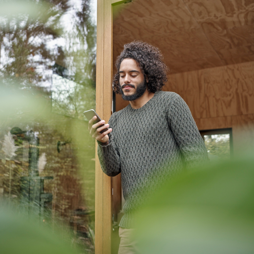 A creative professional leans against a doorway, sharing a large video over WhatsApp from a shoot location.