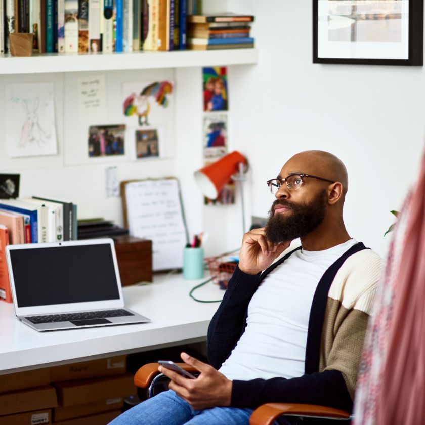 Person sits in a home office, holding a mobile device and thinking about how to recover their lost offline files.