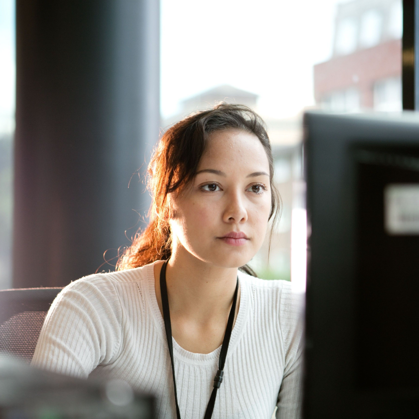 A person looks at their monitor on a desktop computer in an office environment.