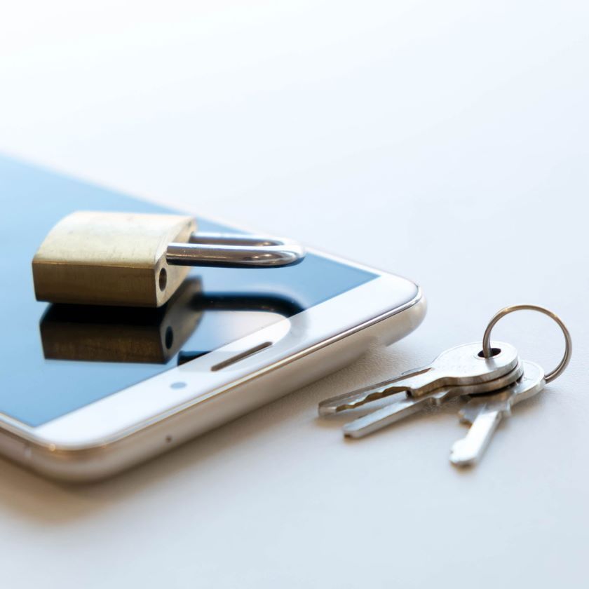 A padlock and set of keys rest on top of a phone.