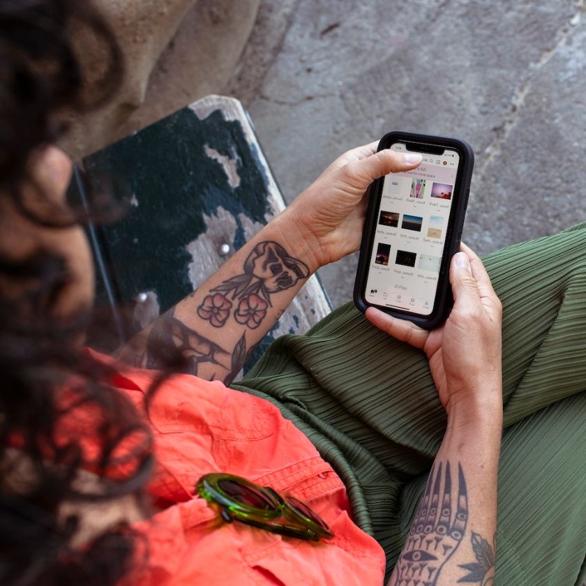 A person holding their phone on their lap, browsing photos from a photoshoot and preparing to share them with a client.